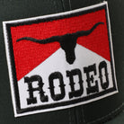 Rodeo patch mid profile trucker hat in black and khaki, side view